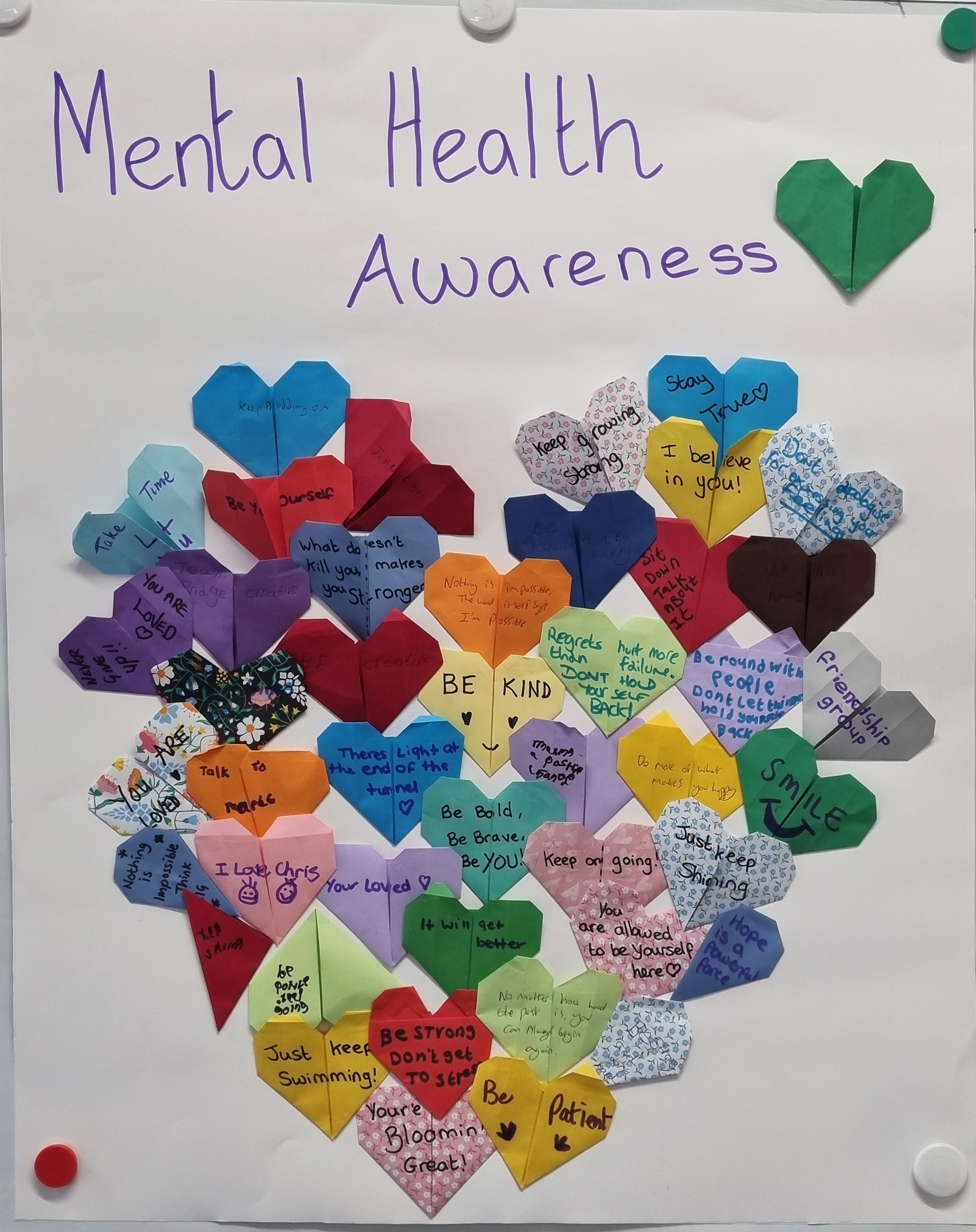 Piece of artwork featuring origami hears with positive messages written on them